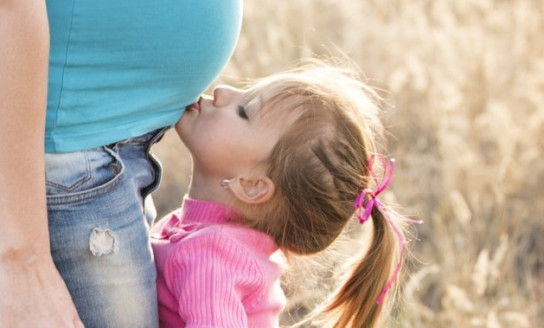 girl in pink sweater and grey jeans kissing tummy of 160776 v3