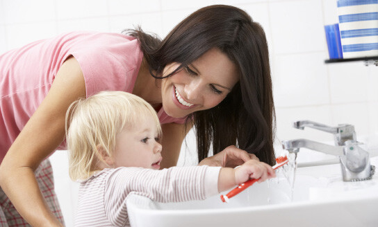 Toddler brushing teeth with mother: Image by Colgate